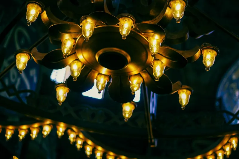 A vintage ornate chandelier with many glowing bulbs.